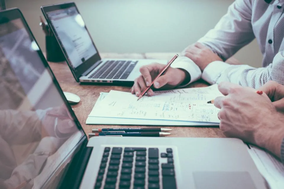 Mesa de trabajo con dos ordenadores portátiles y notas