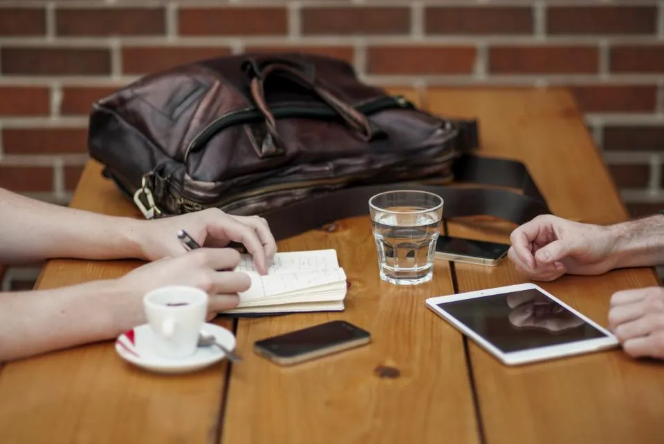 Reunión en una mesa con un café y una tableta